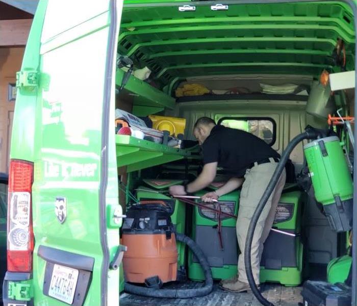 an employee in a SERVPRO van with water damage equipment